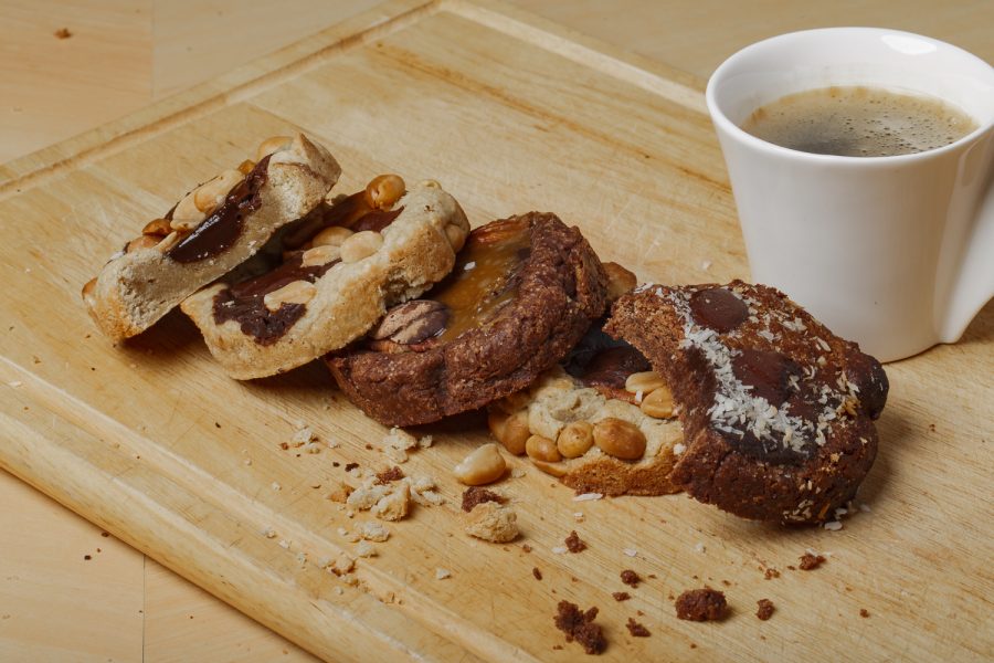 5 cookies cacahuète et chocolat avec une tasse de café sur une planche en bois